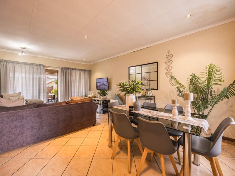 Spacious open-plan living and dining area featuring tiled flooring, recessed lighting, and sliding glass doors leading to an outdoor patio space.