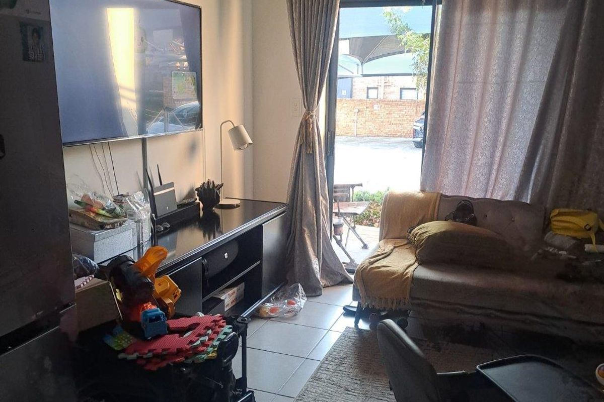 A living room area featuring tiled flooring and a sliding glass door providing access to the exterior.