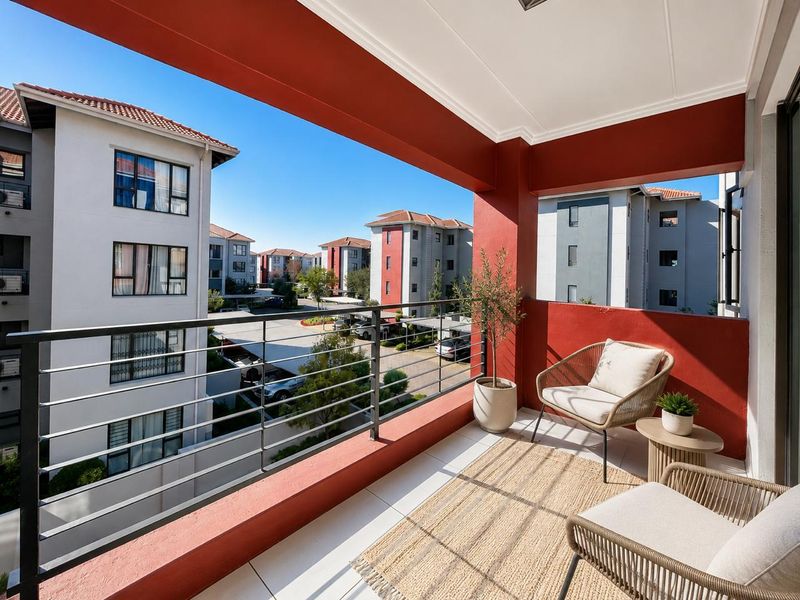 A well-maintained covered balcony featuring tiled flooring, a modern metal balustrade, and views over the apartment complex grounds.
