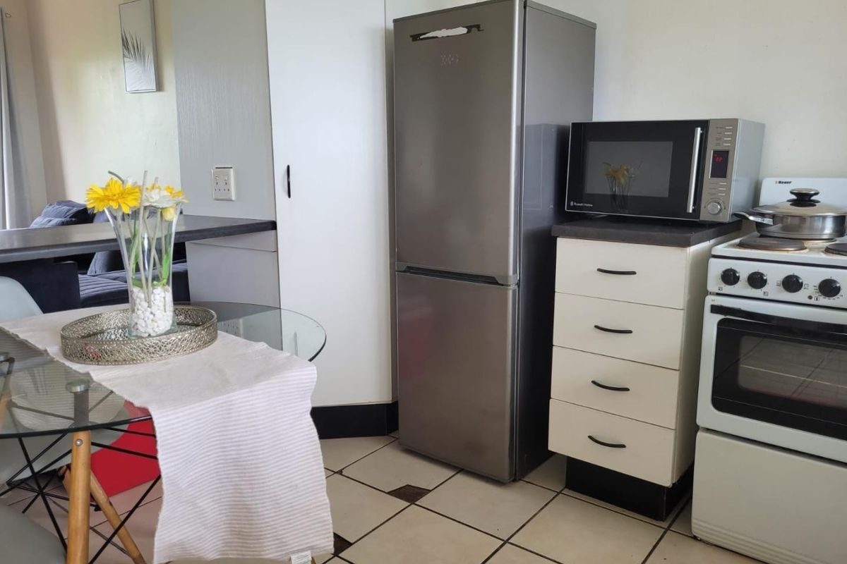 A compact kitchen area featuring tiled flooring, built-in cabinetry, and a freestanding stove, offering a functional layout for daily meal preparation.