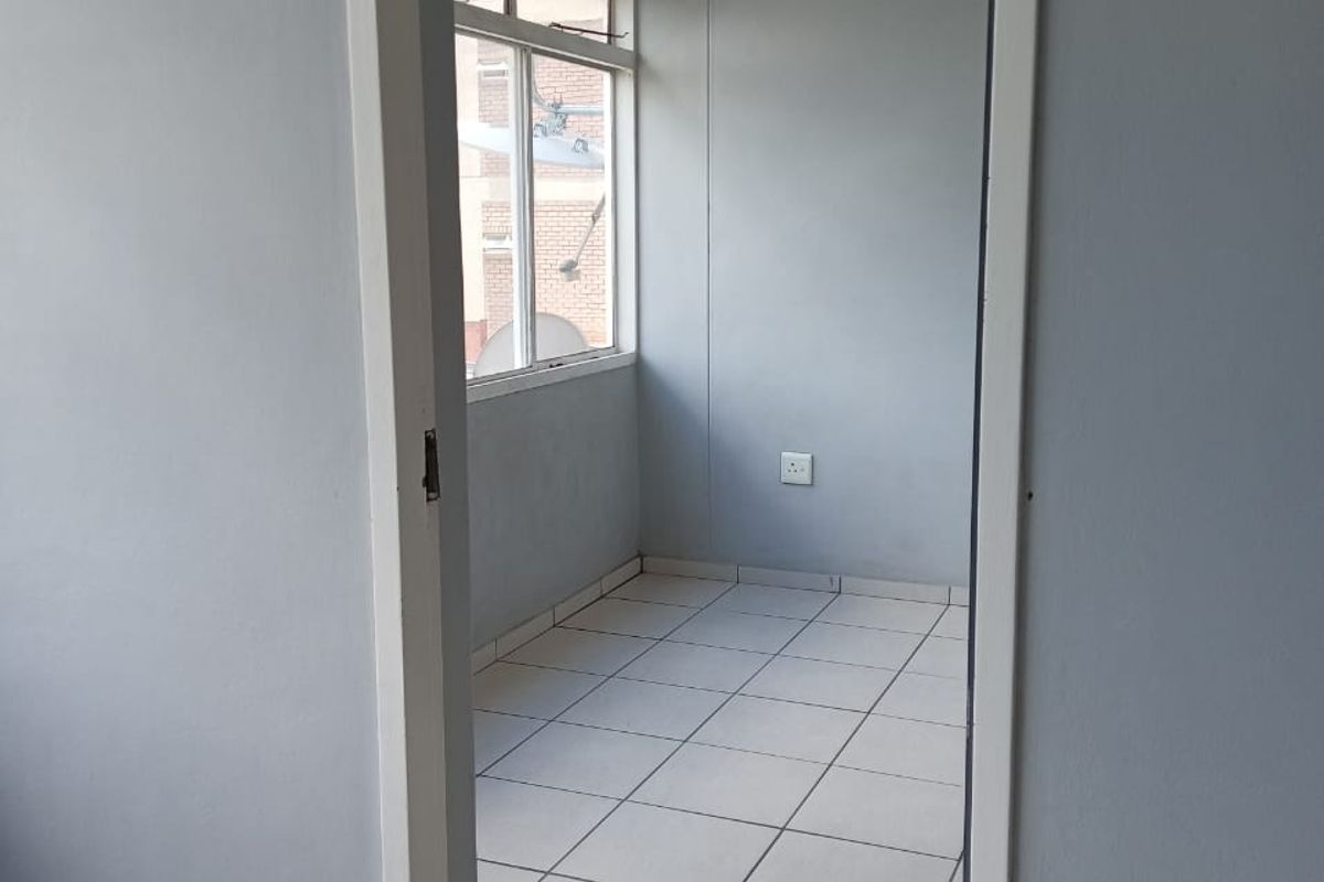 An empty bedroom featuring tiled flooring and a window, providing a blank canvas for potential interior design and renovation.