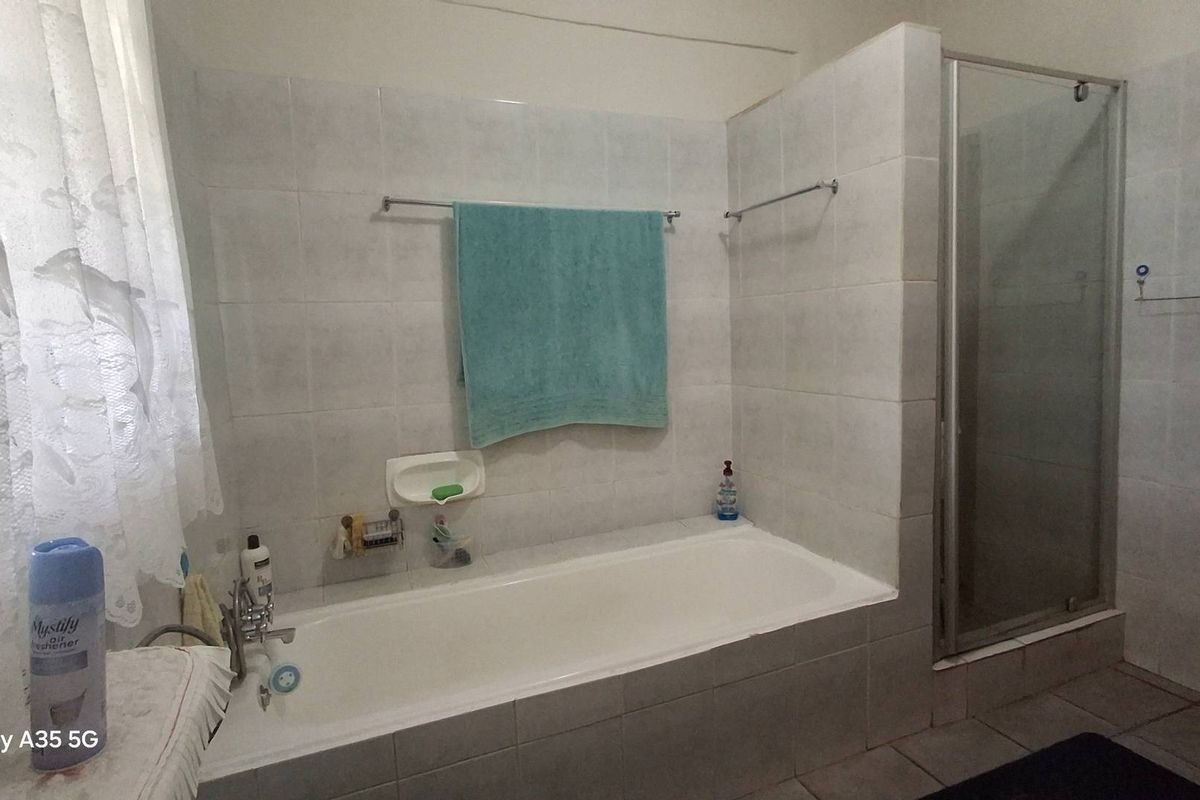 A functional bathroom featuring a built-in bathtub, separate glass-enclosed shower, and tiled wall finishes.