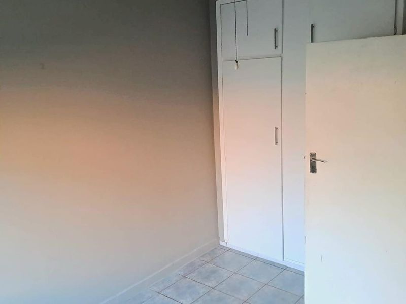 A vacant bedroom featuring tiled flooring, built-in cupboards, and neutral wall tones, offering a blank canvas for personalization.