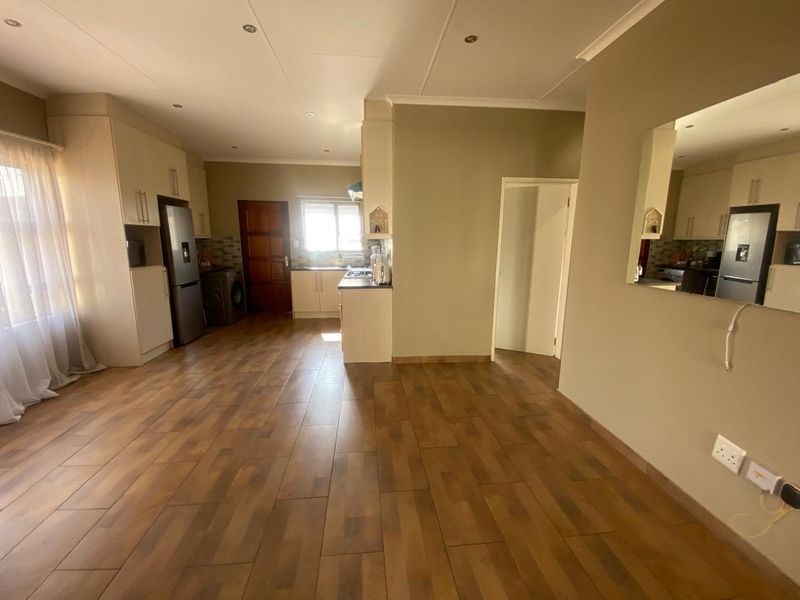An open-plan kitchen and living area featuring tiled flooring, built-in cabinetry, and neutral wall finishes, offering a functional and versatile living space.