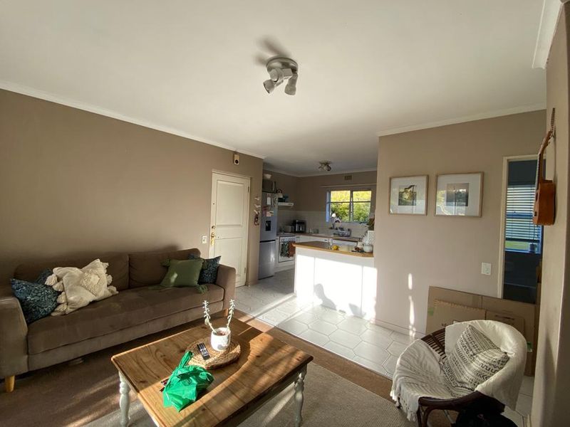 Open plan living area featuring a functional kitchen with tiled flooring, cabinetry, and built-in appliances, seamlessly connected to the lounge space.