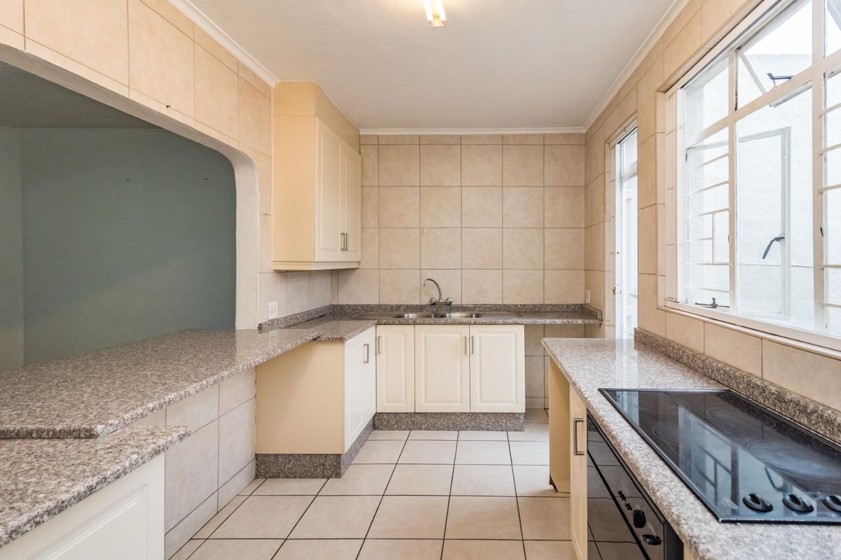 Functional kitchen featuring granite countertops, built-in cabinetry, electric hob, oven, and ceramic tile finishes throughout.
