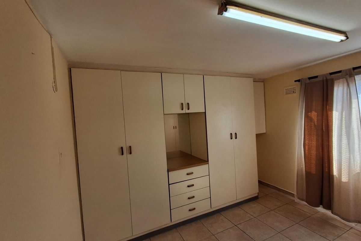 A bedroom featuring built-in cupboards with integrated drawers and shelving, tiled flooring, and a fluorescent light fixture.