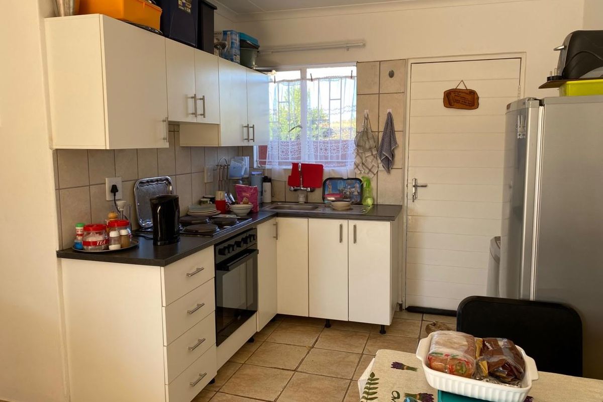 Functional kitchen featuring white cabinetry, laminate countertops, built-in oven and hob, tiled backsplash, and direct access to the exterior.