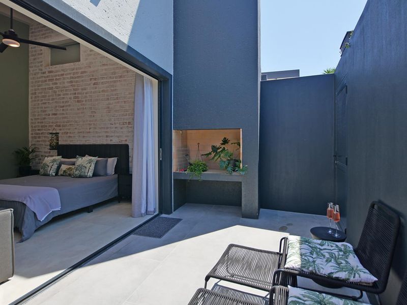 A modern patio featuring a built-in braai and seamless transition to the bedroom through large sliding glass doors.