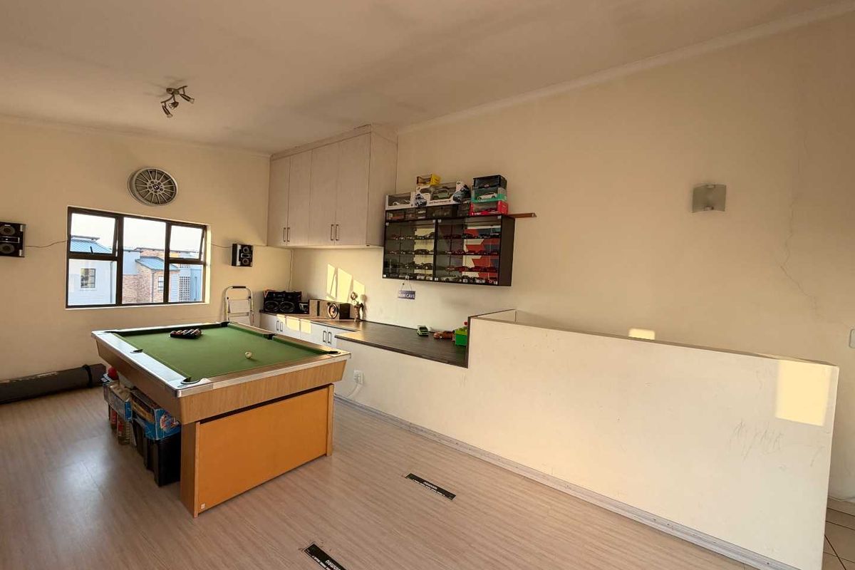 A multi-purpose living area featuring laminate flooring, built-in cabinetry, and a large window, offering a versatile space for recreation or relaxation.