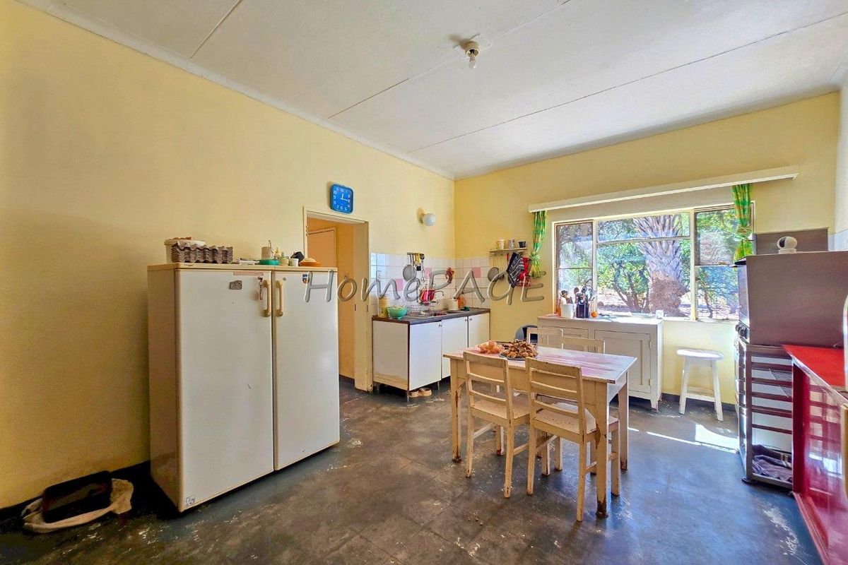 A dated kitchen featuring original cabinetry, tiled splashbacks, and a large window, offering significant potential for a modern renovation and layout update.