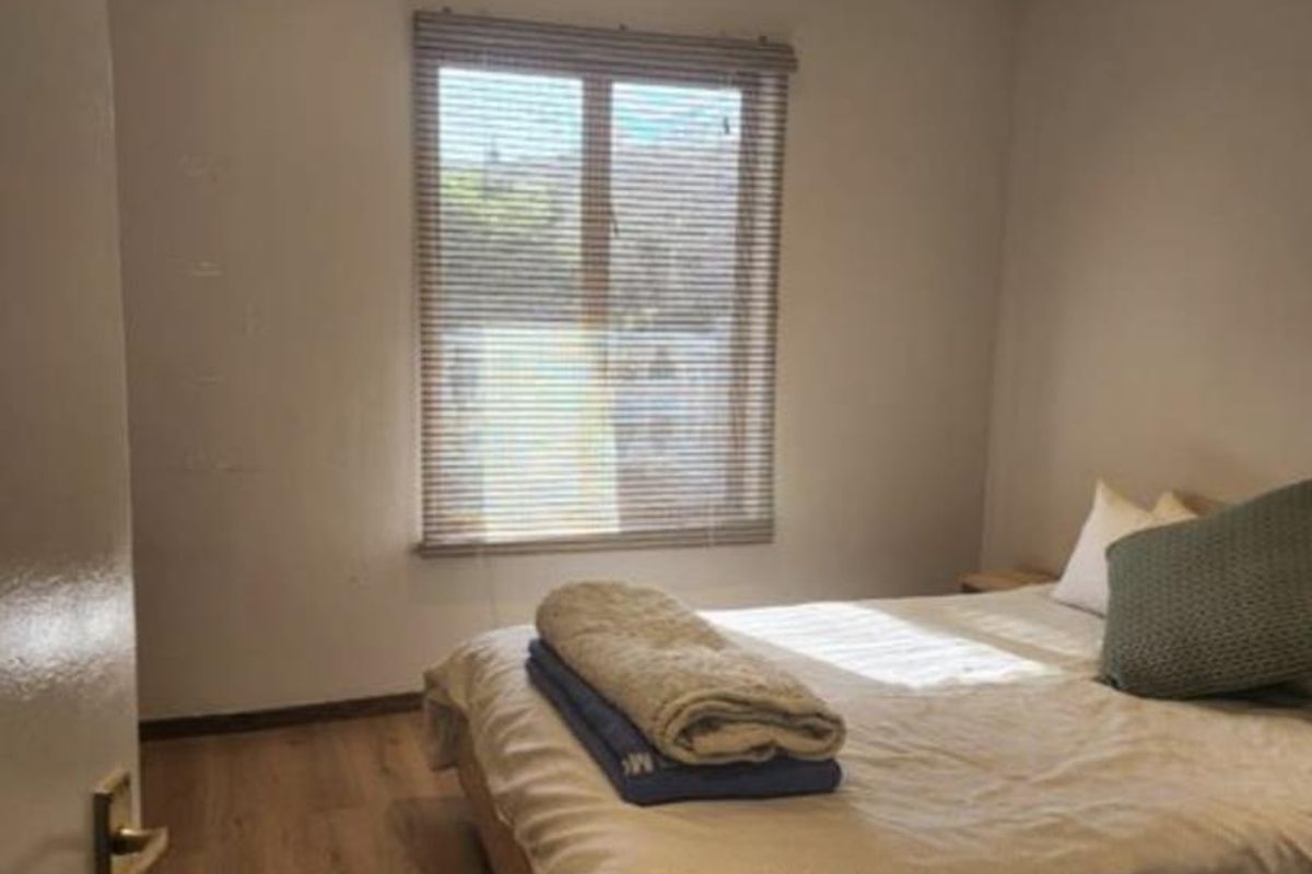 A functional bedroom featuring laminate flooring, a ceiling fan, and recessed lighting, providing a comfortable and neutral living space.
