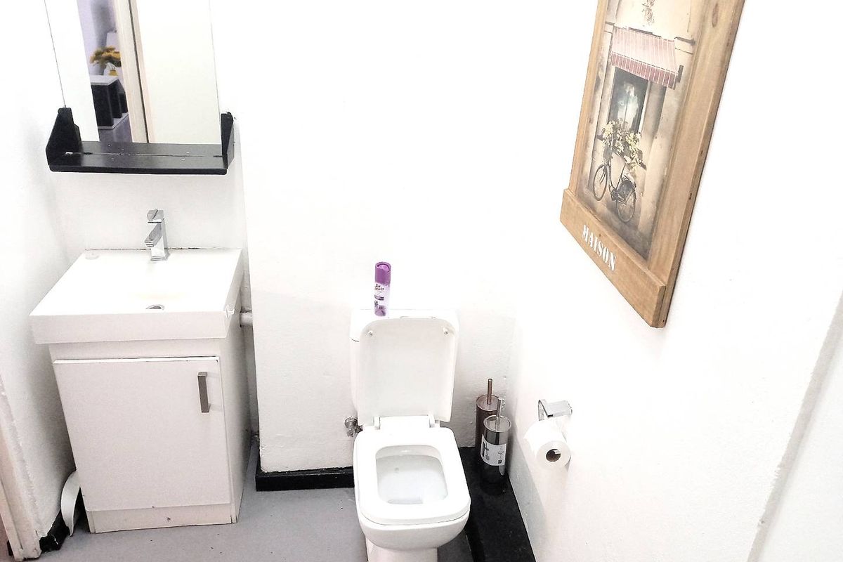 A compact bathroom featuring a white vanity with integrated basin, a modern toilet, and a wall-mounted mirror.