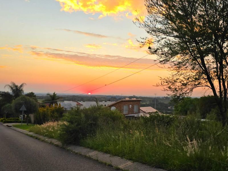 A scenic street view of the residential area at sunset, featuring paved roads and surrounding landscape.
