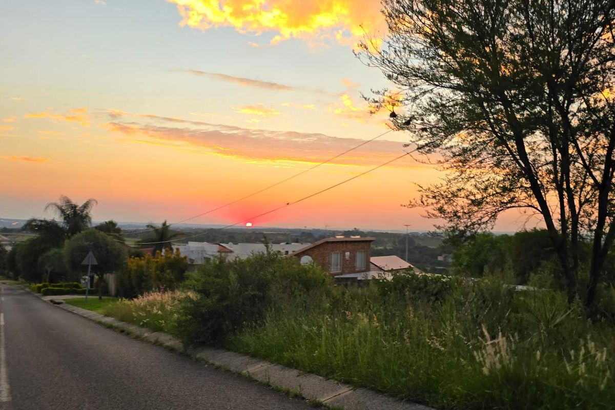A scenic street view of the residential area at sunset, featuring paved roads and surrounding landscape.