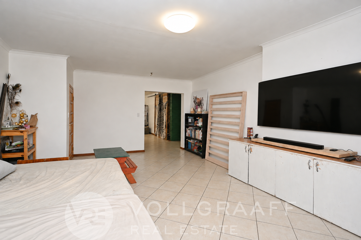 Spacious living area featuring neutral tiled flooring, built-in storage cabinetry, and a clean, open layout suitable for various furniture arrangements.
