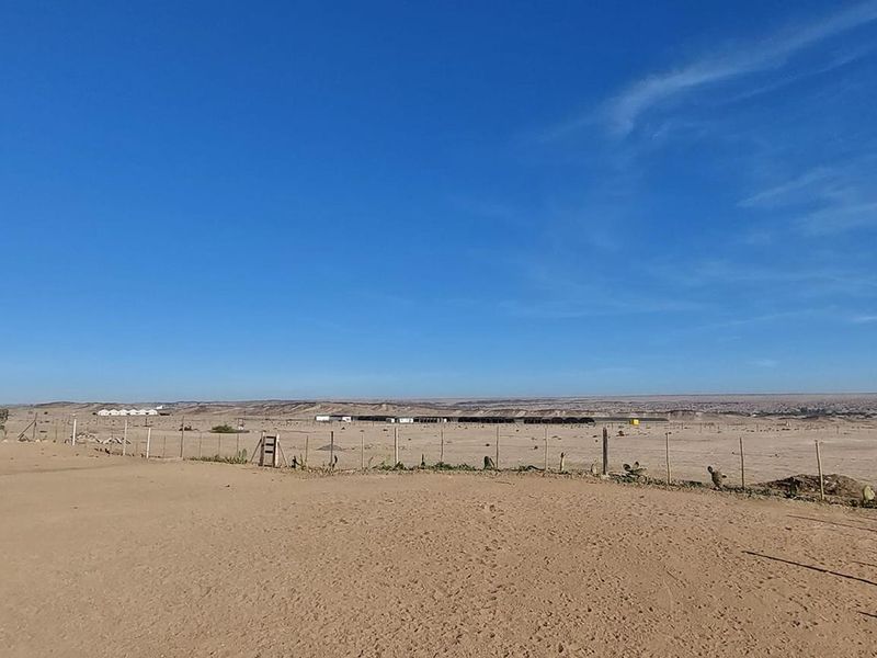 Expansive landscape view overlooking the arid small holding property with perimeter wire fencing.