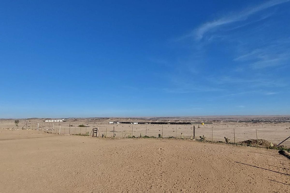 Expansive landscape view overlooking the arid small holding property with perimeter wire fencing.