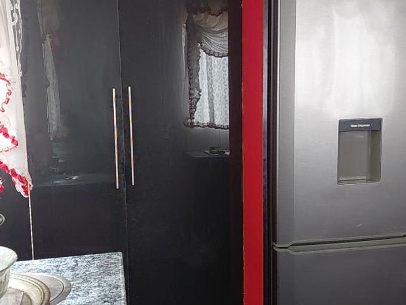 A kitchen area featuring dark cabinetry with red accents, granite countertops, and tiled flooring, providing a functional workspace.