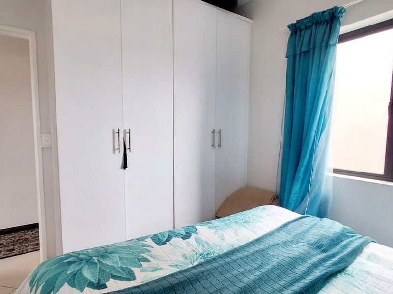 A bedroom featuring white built-in cupboards and a window, providing functional storage and natural light.