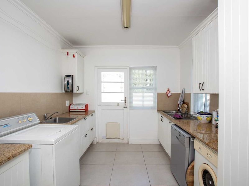 Functional laundry room featuring built-in cabinetry, granite countertops, stainless steel sink, and direct access to the exterior.