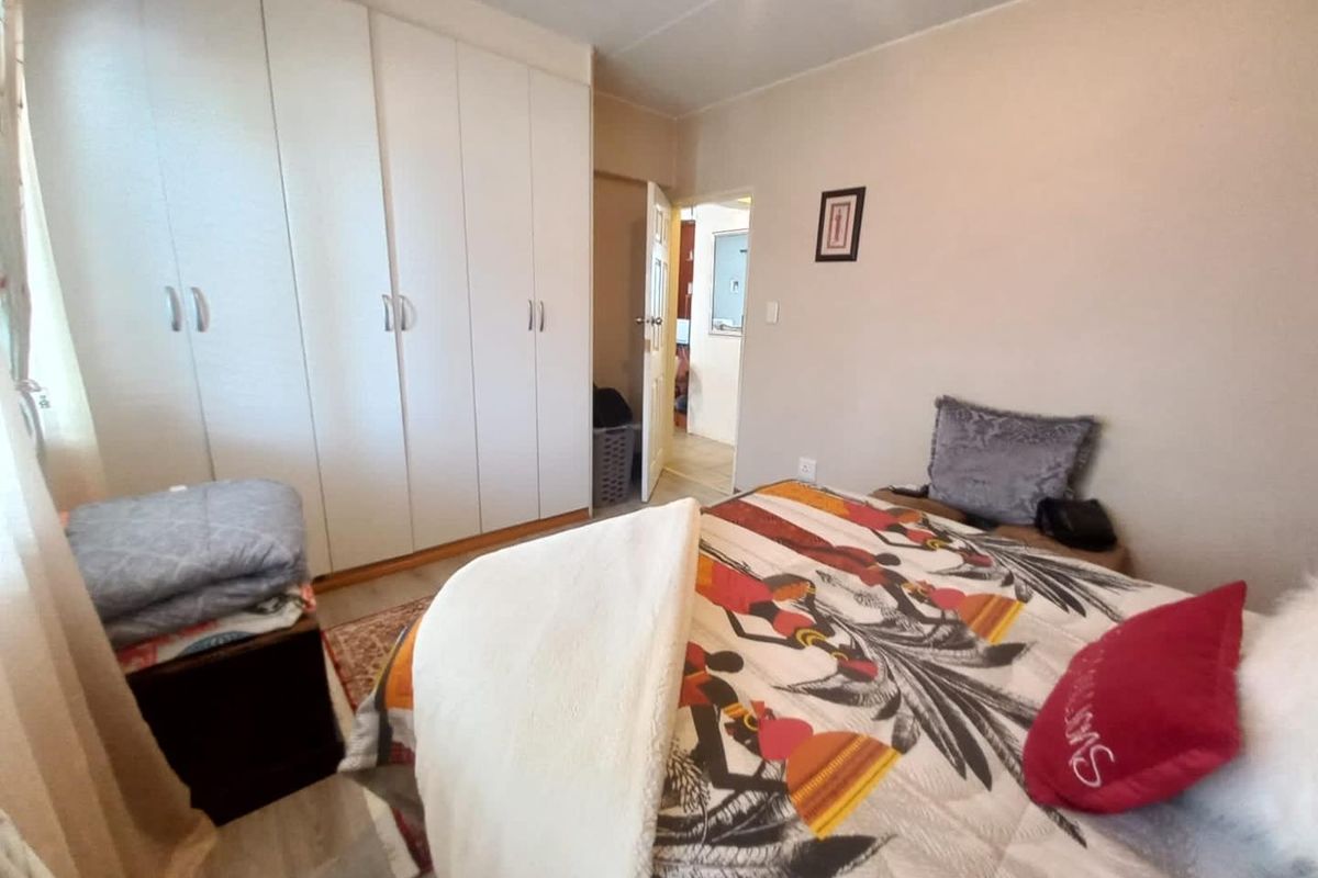 A functional bedroom featuring ample built-in cupboard storage and neutral wall finishes, providing a comfortable and practical living space.