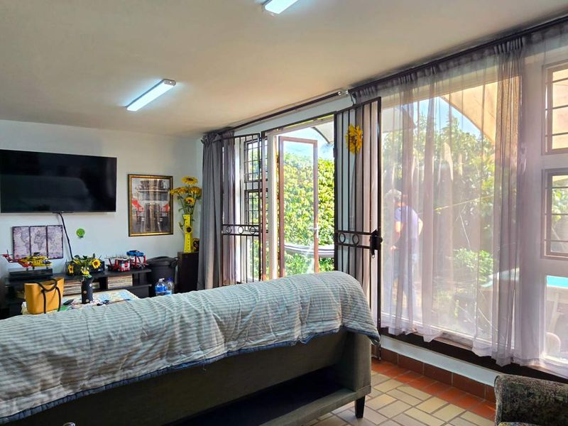 A living room featuring tiled flooring, fluorescent lighting, and a security gate leading to an outdoor area.