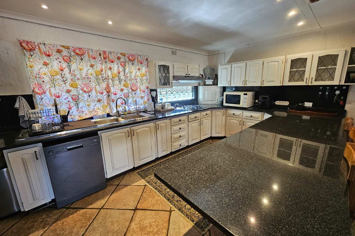 Spacious kitchen featuring granite countertops, extensive built-in cabinetry, and tiled flooring, offering a functional layout with ample workspace.