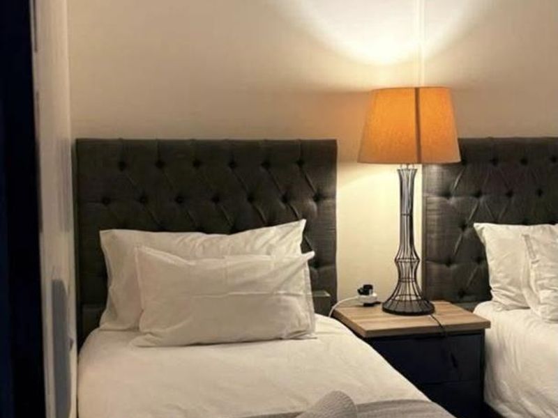 A compact bedroom featuring a mirrored wall and twin bed setup, providing a functional sleeping space.