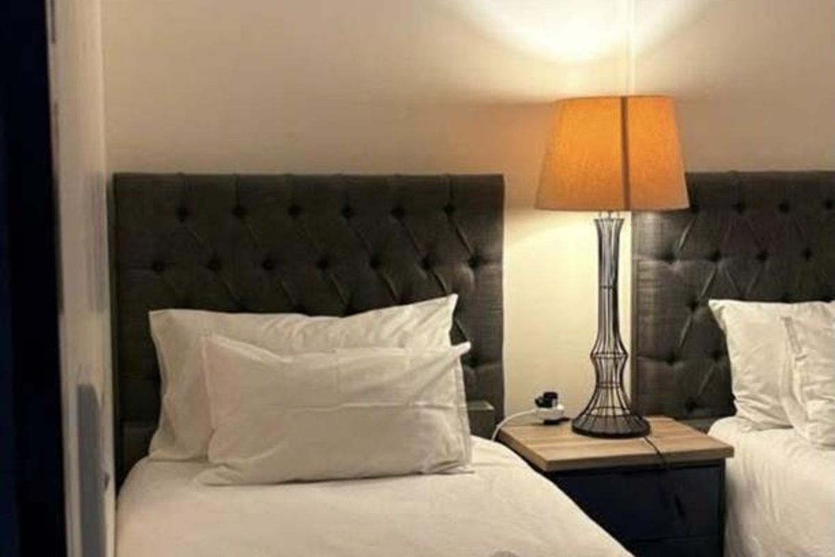 A compact bedroom featuring a mirrored wall and twin bed setup, providing a functional sleeping space.