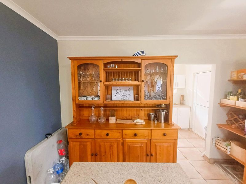 A kitchen area featuring tiled flooring and a view through to a secondary utility or scullery space with white cabinetry.