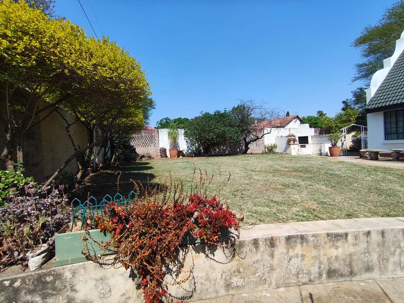 A spacious backyard garden featuring a lawn, perimeter boundary walls, and a built-in outdoor braai area.