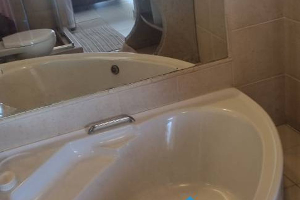 A bathroom featuring a corner soaking tub, a pedestal-style vanity with a vessel sink, and large wall-mounted mirrors.