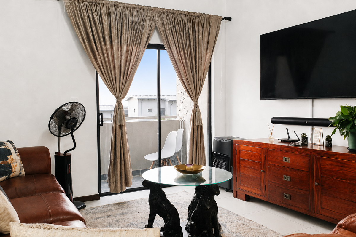 A well-lit living room featuring tiled flooring and a sliding glass door that provides access to an outdoor balcony area.