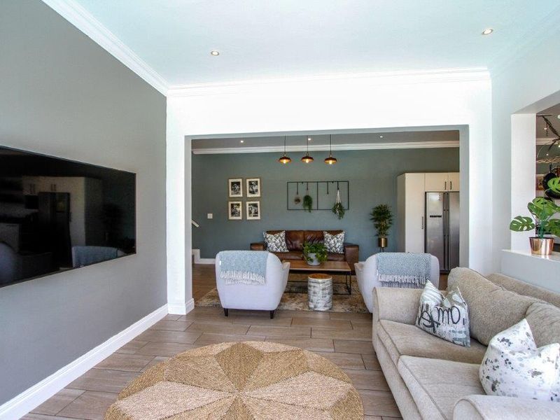Spacious open-plan living area featuring modern tiled flooring, recessed downlighting, and elegant crown molding, creating a bright and cohesive flow between living spaces.