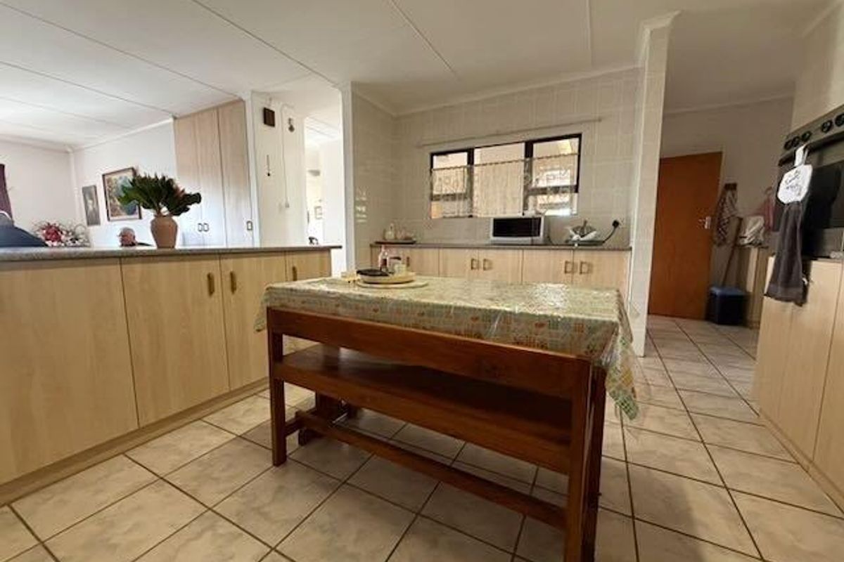 A functional kitchen featuring light wood cabinetry, tiled flooring, and a central island, offering a practical layout with ample storage space.