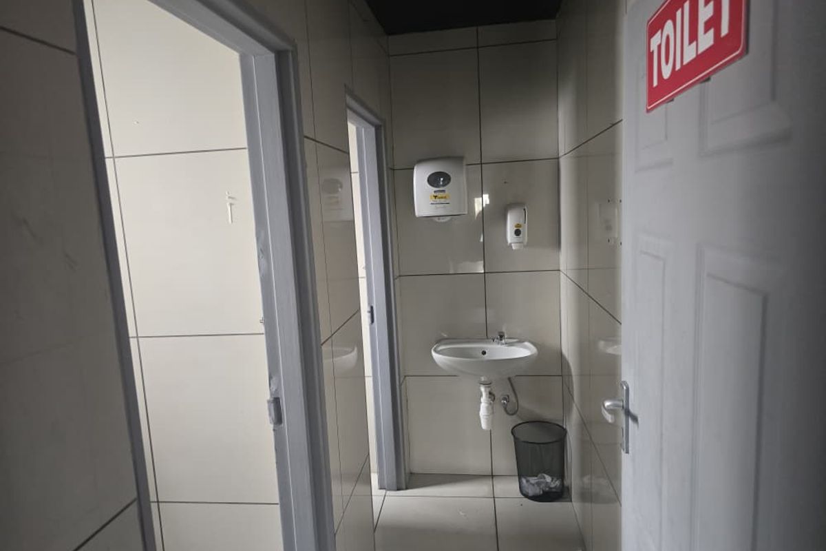 A functional commercial restroom facility featuring tiled walls, a wall-mounted basin, and soap dispensers.