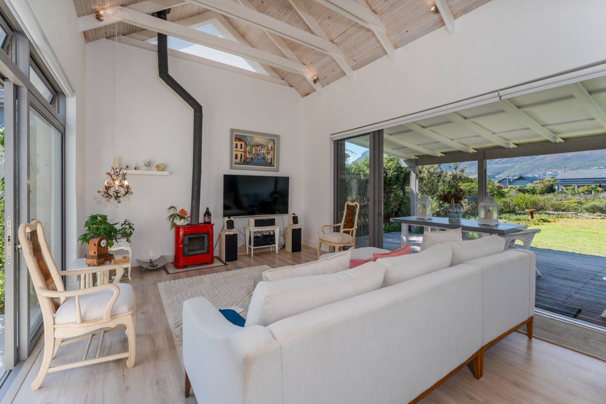 Bright living room featuring a vaulted timber ceiling, exposed beams, a red wood-burning fireplace, and large sliding doors opening to a covered patio.
