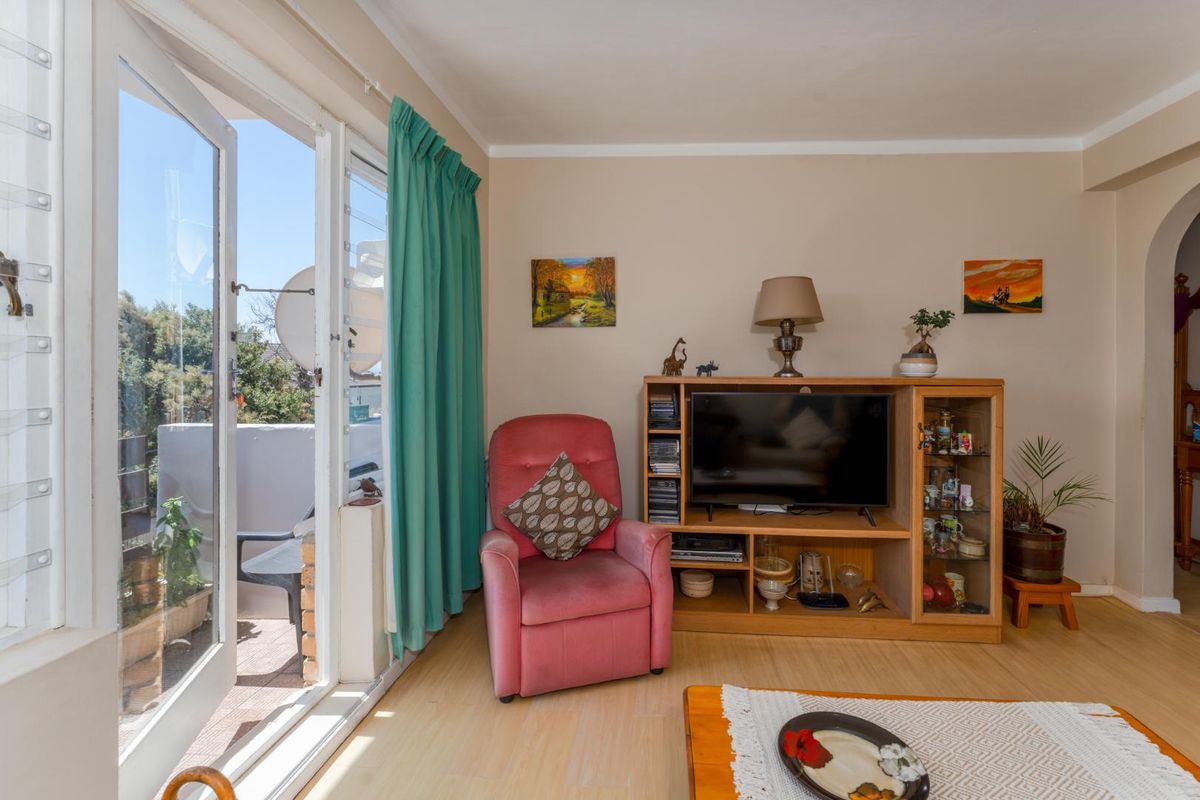 A living room featuring light-toned laminate flooring and double glass doors providing direct access to an outdoor balcony area.