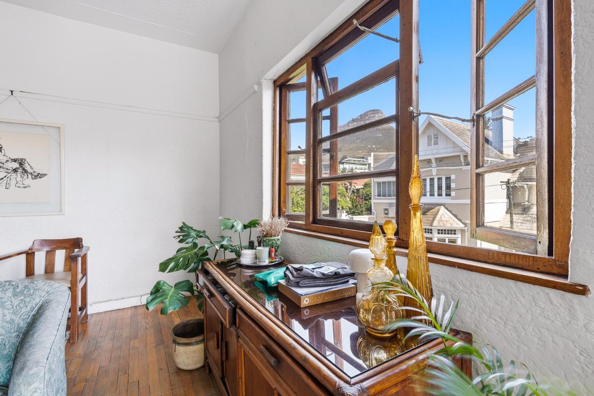 A bedroom featuring original timber-framed casement windows, hardwood flooring, and views of the surrounding neighborhood and mountain.