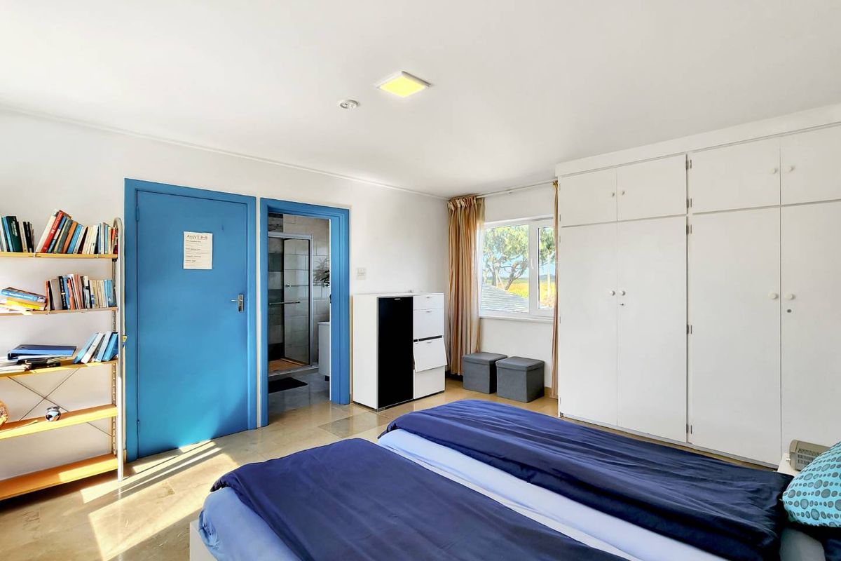 A functional bedroom featuring built-in white cupboards, tiled flooring, and direct access to an en-suite bathroom.