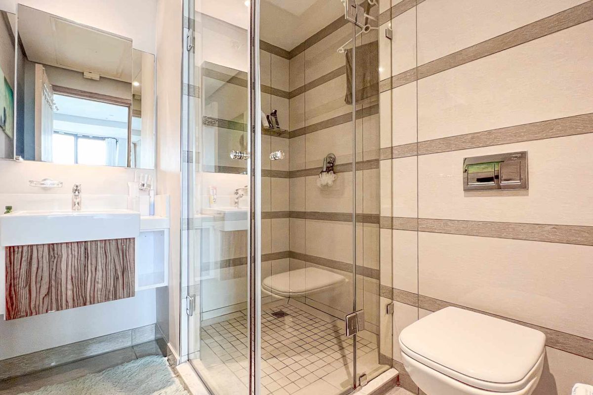 Modern bathroom featuring a wall-mounted vanity, a glass-enclosed shower with a built-in seat, and a wall-hung toilet with a concealed cistern.