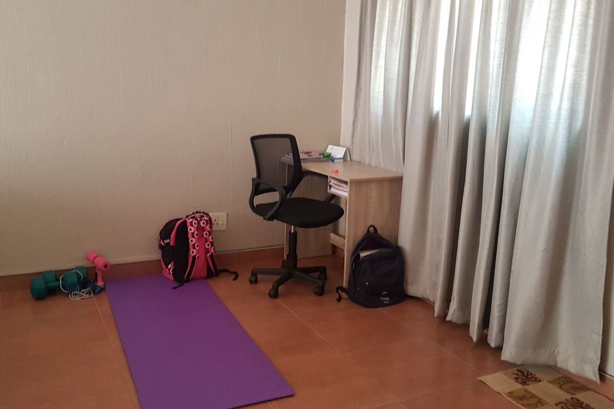 A simple bedroom featuring tiled flooring and window curtains, providing a functional space for rest or study.