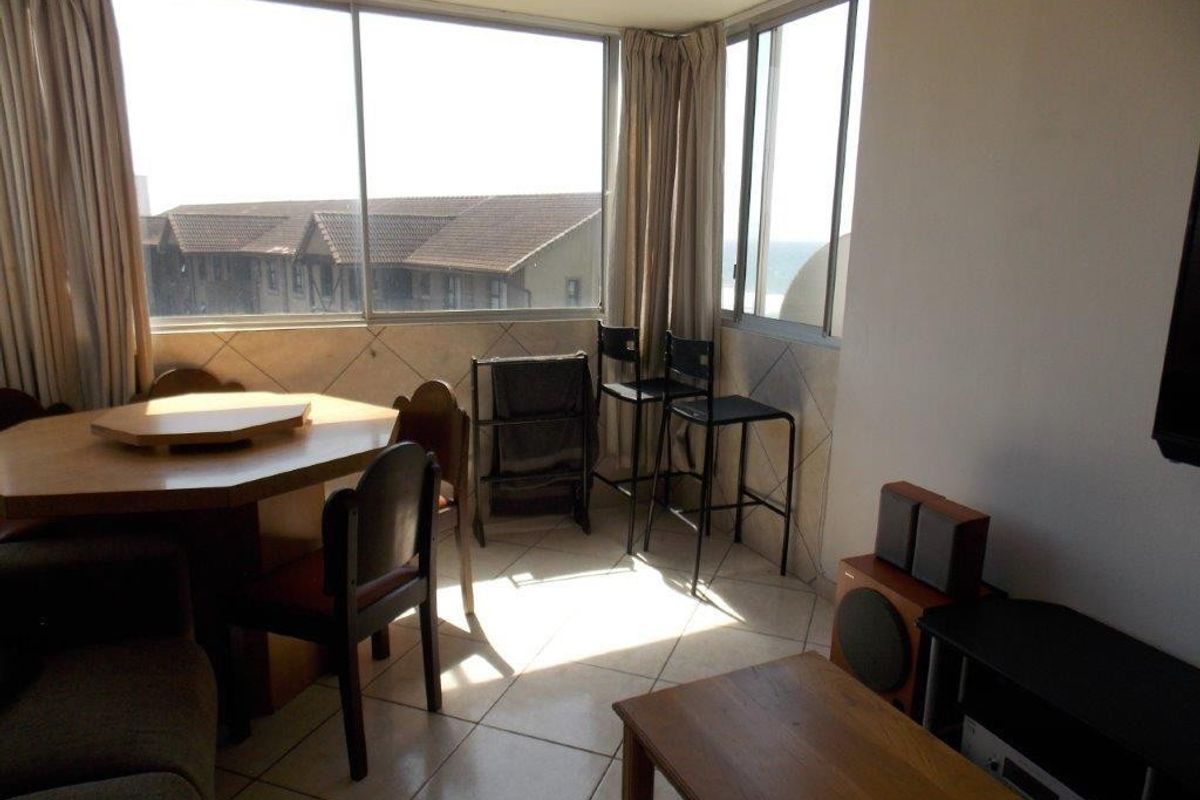 A living area featuring large windows with natural light and tiled flooring, offering a bright space with potential for modern updates.