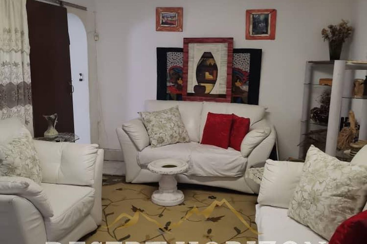 A living room space featuring basic overhead lighting and standard wall finishes, currently furnished with a seating arrangement.