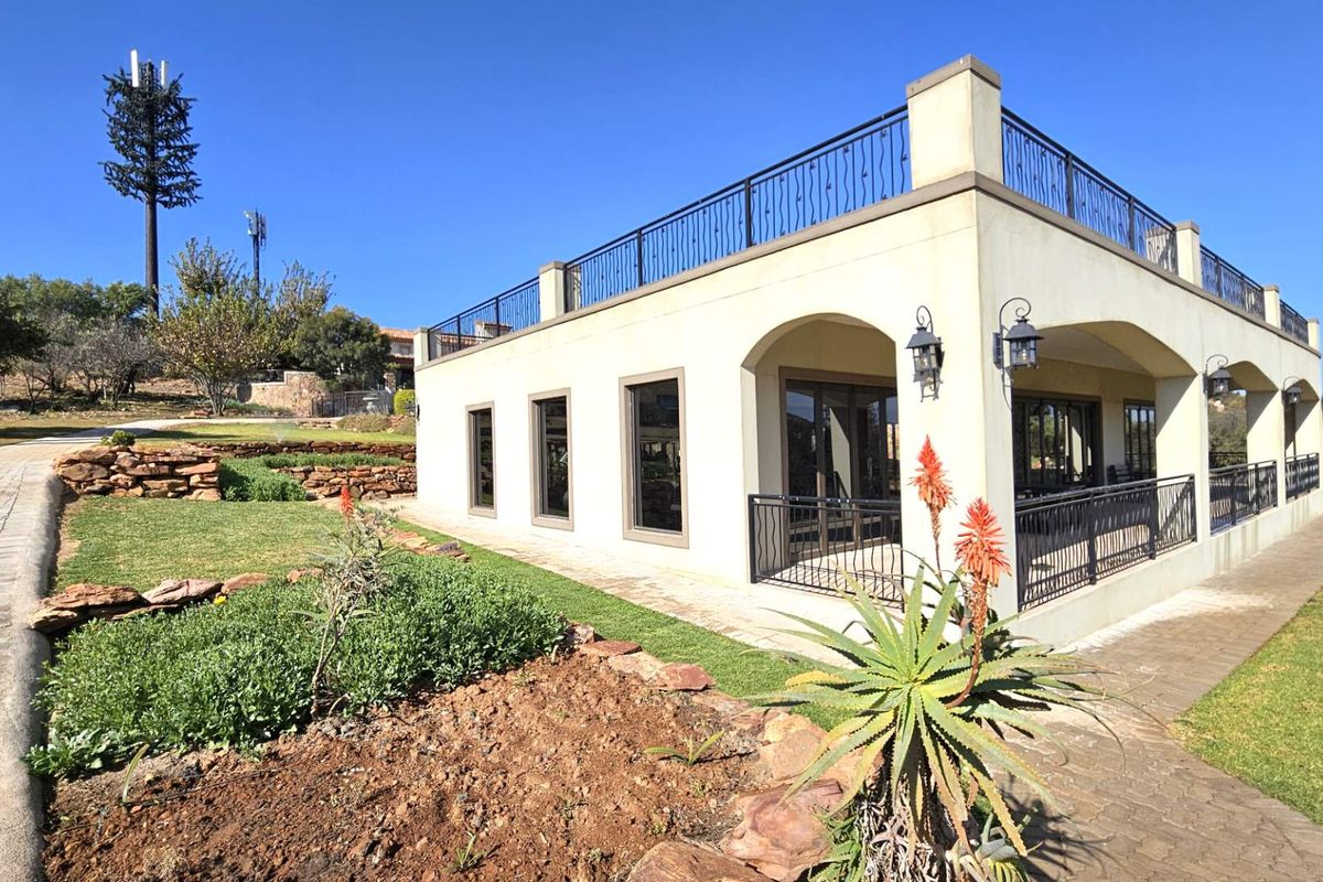 Exterior view of a modern residence featuring a spacious rooftop terrace with wrought iron railings, arched patio openings, and landscaped garden surroundings.