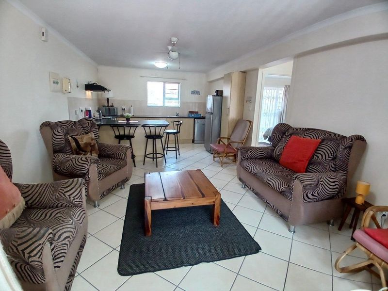 Open-plan living area featuring a kitchen with breakfast counter, tiled flooring, and ceiling fan, creating a functional and connected living space.