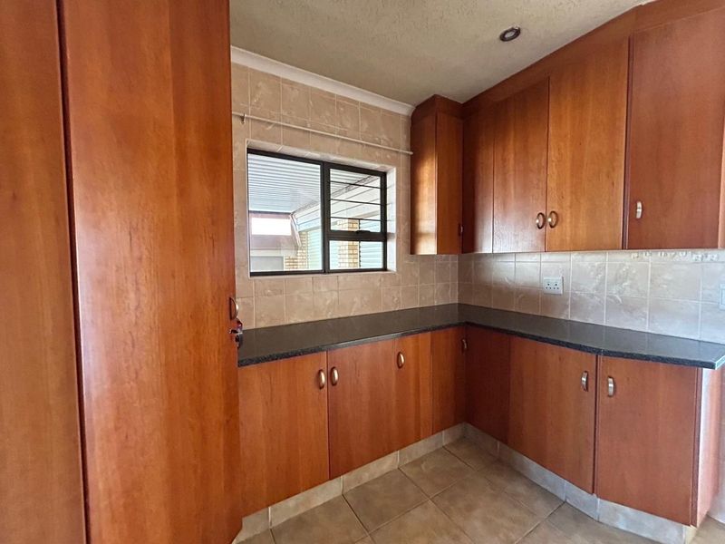 A functional kitchen featuring wooden cabinetry, granite countertops, and tiled backsplash, offering a clean and practical workspace.