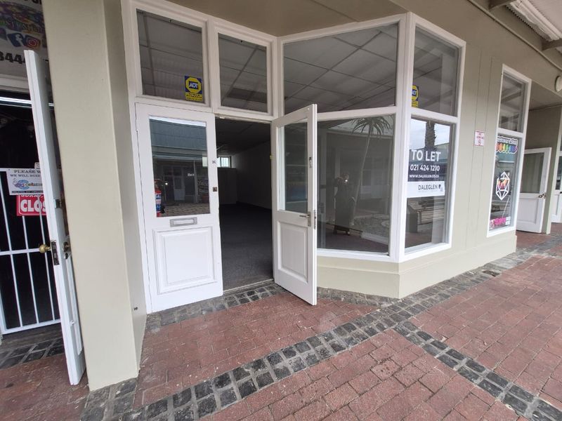 Front entrance of a retail shop featuring large display windows, paved exterior walkway, and double glass doors.