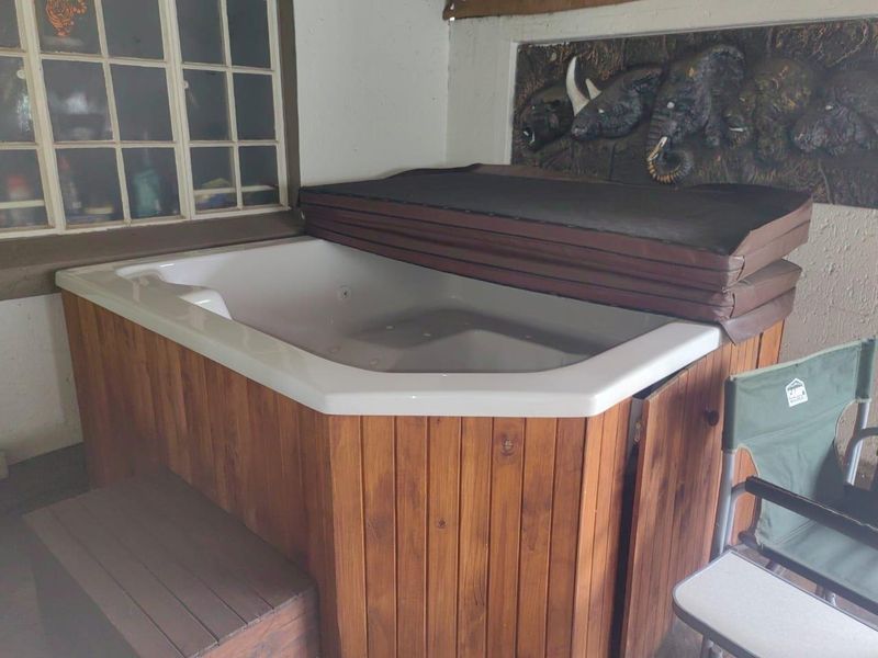 A covered patio area featuring a built-in jacuzzi with wooden paneling and a decorative wall relief.